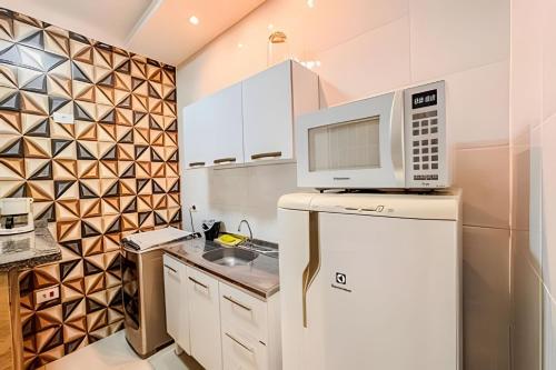 a kitchen with a microwave on top of a refrigerator at Sobrado encantador no centro, ar cond e vaga in Ourinhos