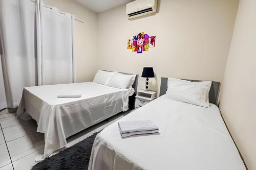 two beds in a room with white walls at Jardim Florida 1 in Ourinhos