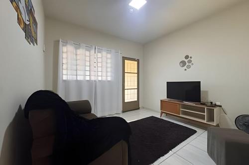 a living room with a couch and a television at Jardim Florida 1 in Ourinhos