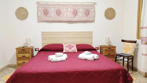 a bedroom with a red bed with two towels at Da Tziu Efisiu Mare e Relax nel Sinis in Baratili San Pietro