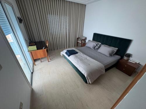 a bedroom with a bed with a green headboard at Luna Loft in La Soukra