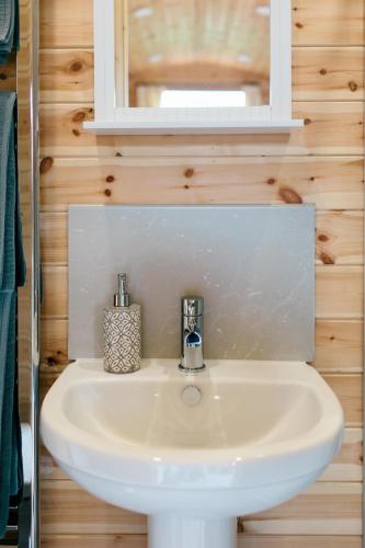 a bathroom with a white sink and a mirror at Shepherd's Huts in Barley Meadow at Spring Hill Farm in Oxford