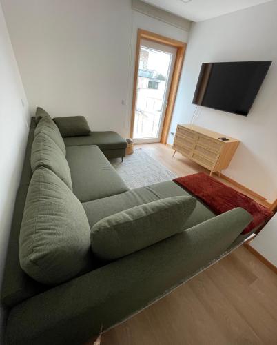 a living room with a green couch and a flat screen tv at Casa do Rio in Aguçadoura