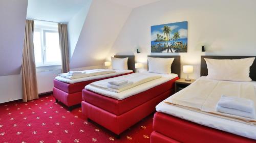 2 Betten in einem Zimmer mit rotem Teppich in der Unterkunft Hotel Maurer in Karlsruhe