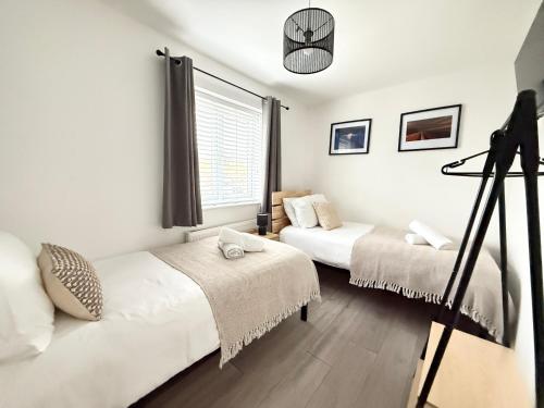 Un dormitorio con dos camas y una ventana. en 2 Bed Home Port Talbot - Perfect For Contractors & Long Stays, en Port Talbot