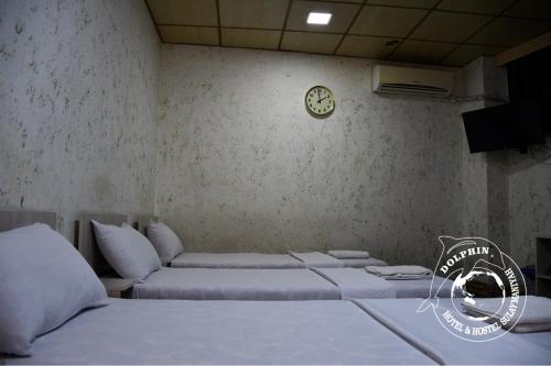 a room with two beds and a clock on the wall at Dolphin Hotel & Hostel in As Sulaymānīyah