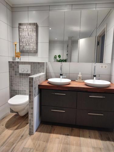 a bathroom with two sinks and a toilet and a mirror at Soverom i enebolig in Kristiansand