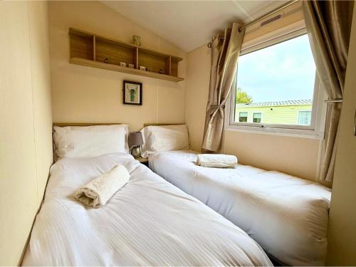 two beds in a room with a window at Lovely Hot Tub Caravan in Northumberland, Free Golf Access, Dog Friendly in Swarland