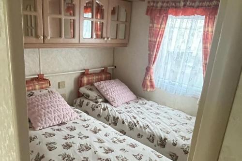 two twin beds in a room with a window at 2 Bedroom Caravan - Sleeps 6 - Seaside Parking in Kinmel Bay