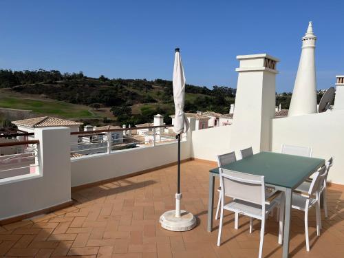 a patio with a table and chairs and an umbrella at Luxury private property-pool, unique sun roof, free wifi in Budens