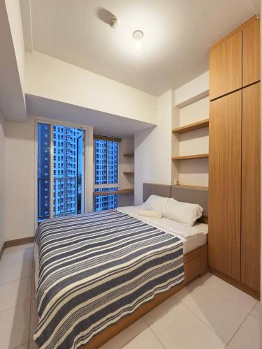 a bedroom with a large bed and two windows at PIK 2 Tokyo Riverside 2 BEDROOM in Gedong