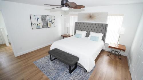 a white bedroom with a bed and a ceiling fan at The Beach House in Port Saint Lucie
