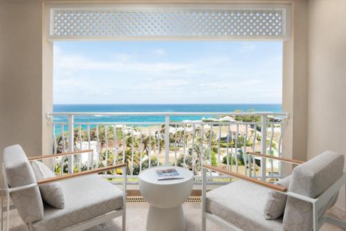 a room with a balcony with a view of the ocean at The Crane Resort in Saint Philip