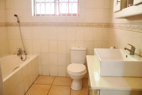 a bathroom with a toilet and a tub and a sink at Elroiairbnb in Amanzimtoti