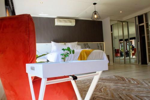 a bedroom with a white bed and a red chair at Elroiairbnb in Amanzimtoti