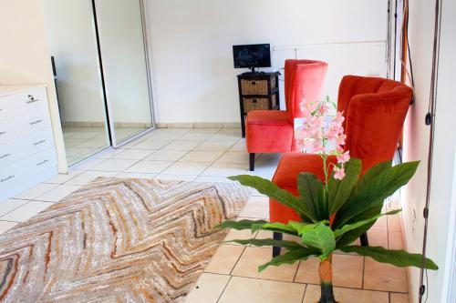 a living room with two red chairs and a plant at Elroiairbnb in Amanzimtoti