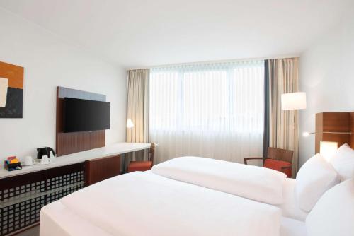 a hotel room with two beds and a television at NH Frankfurt Niederrad in Frankfurt/Main