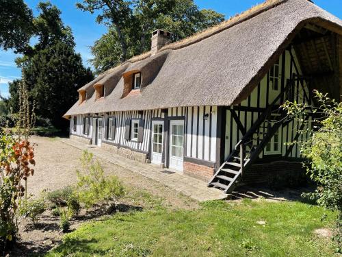 an old house with a thatched roof and a yard at Clos de Leger in Pleine-sève