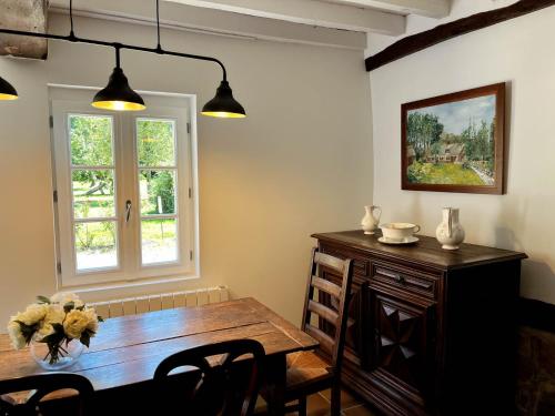 a dining room with a wooden table and a window at Clos de Leger in Pleine-sève