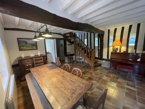 a dining room with a wooden table and a piano at Clos de Leger in Pleine-sève