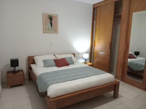a bedroom with a large bed and a mirror at Resid Home ACACIA in Moanda