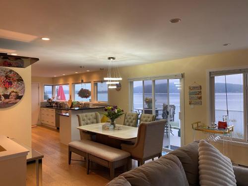 a kitchen and a living room with a table and chairs at Beachbreeze Panoramic Oceanview 4BR 3BA Romantic Sunrise & Celestial Views in Mill Bay