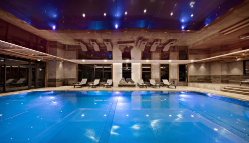 a swimming pool in a hotel with blue lighting at MGM Hôtels & Résidences - Résidence Alexane in Samoëns