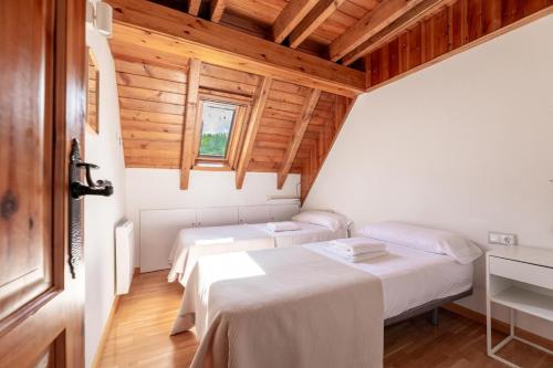 two beds in a room with wooden ceilings at Las casitas de mache - 5F in Cerler