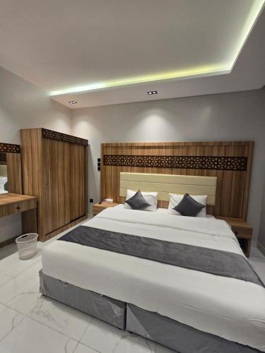a bedroom with a large white bed with wooden walls at شقق المطار in Jeddah