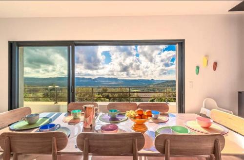 una sala da pranzo con un tavolo e una grande finestra di Villa ALTEA , au cœur du Maquis , 4 chambres , Figari a Figari