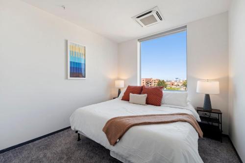 a white bedroom with a bed and a large window at 2BR City Loft Amazing Glass Views in Chicago