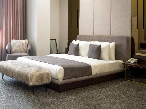 a bedroom with a large bed and a chair at Leork Hotel in Rawalpindi