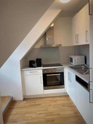 a small kitchen with white cabinets and a staircase at Carillon by BestChoice - Old City - Self Check-in with PARKING option in Graz
