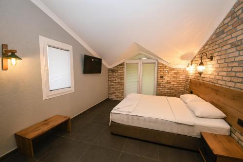a bedroom with a bed and a brick wall at Ballı Butik hotel in Kayakoy