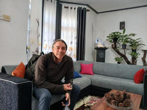 a man sitting on a couch in a living room at Dio Green House NUWRA ELIYA in Nuwara Eliya