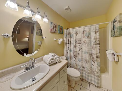 a bathroom with a sink and a toilet and a mirror at Grand Caribbean Perdido Key #101 West in Perdido Key