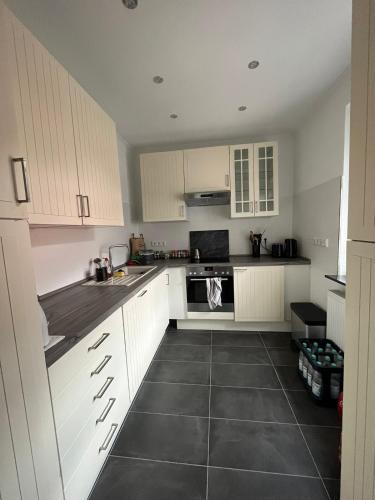 a kitchen with white cabinets and a black tile floor at Sunshine in Groß-Zimmern