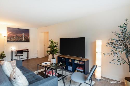 Una sala de estar con un sofá azul y un televisor de pantalla plana. en 2 Bedroom Apartment next to Convention Center!, en Seattle