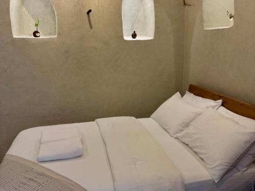 a bedroom with a bed with white sheets and pillows at بيت الصباح نزل وكافيه Bait AlSabah Heritage Inn & Cafe in Birkat al Mawz