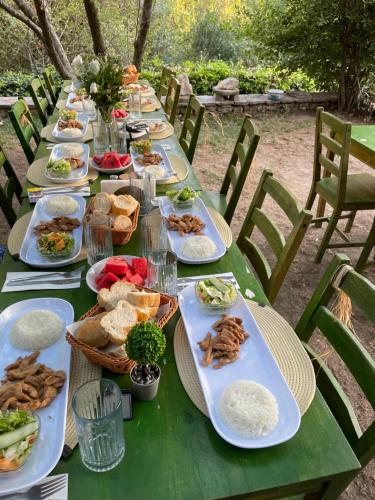 a long green table with plates of food on it at İzmir Yaşam Vadisi Oteli in Burunabat
