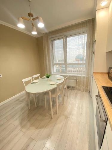 - une cuisine avec une table et des chaises blanches dans la chambre dans l'établissement Only sun, à Astana