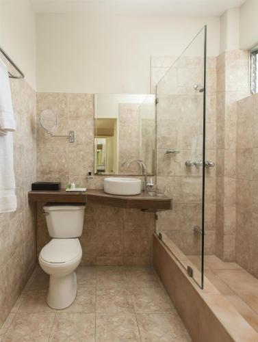 a bathroom with a toilet and a sink and a shower at NH Haiti El Rancho in Port-au-Prince
