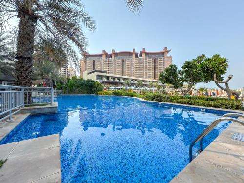 a large swimming pool with a hotel in the background at 2BDR Luxury Apartment in Palm in Dubai