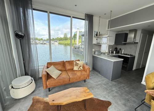 Una sala de estar con un sofá y una cocina. en De Maasterp - Woonboot 2, en Montfort