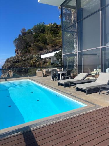 a swimming pool in front of a house at Sea House Madeira in Garajau