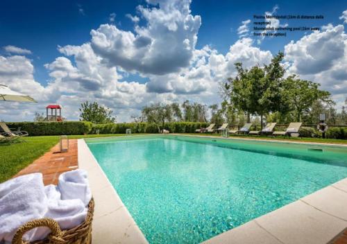 a swimming pool with chairs and a sky with clouds at Villa S.Andrea in San Casciano in Val di Pesa