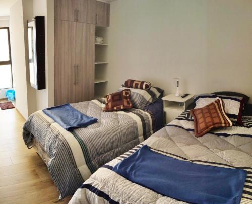 ein Schlafzimmer mit 2 Betten mit Kissen darauf in der Unterkunft Departamento , Ave Paraíso in Cochabamba
