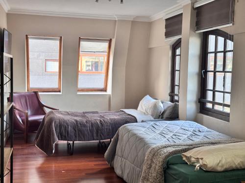 a bedroom with two beds and a chair at Torremolinos departamentos in Temuco