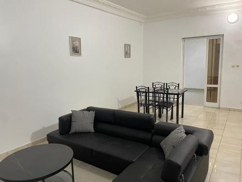 a living room with a black couch and a table at Appartement mbour Saly in Mbour