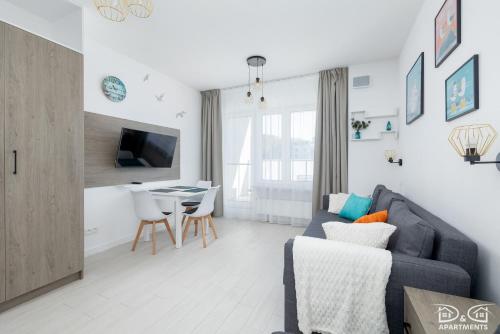 a living room with a blue couch and a table at Mewa Aquamarina Onyx D&D Apartments in Międzyzdroje